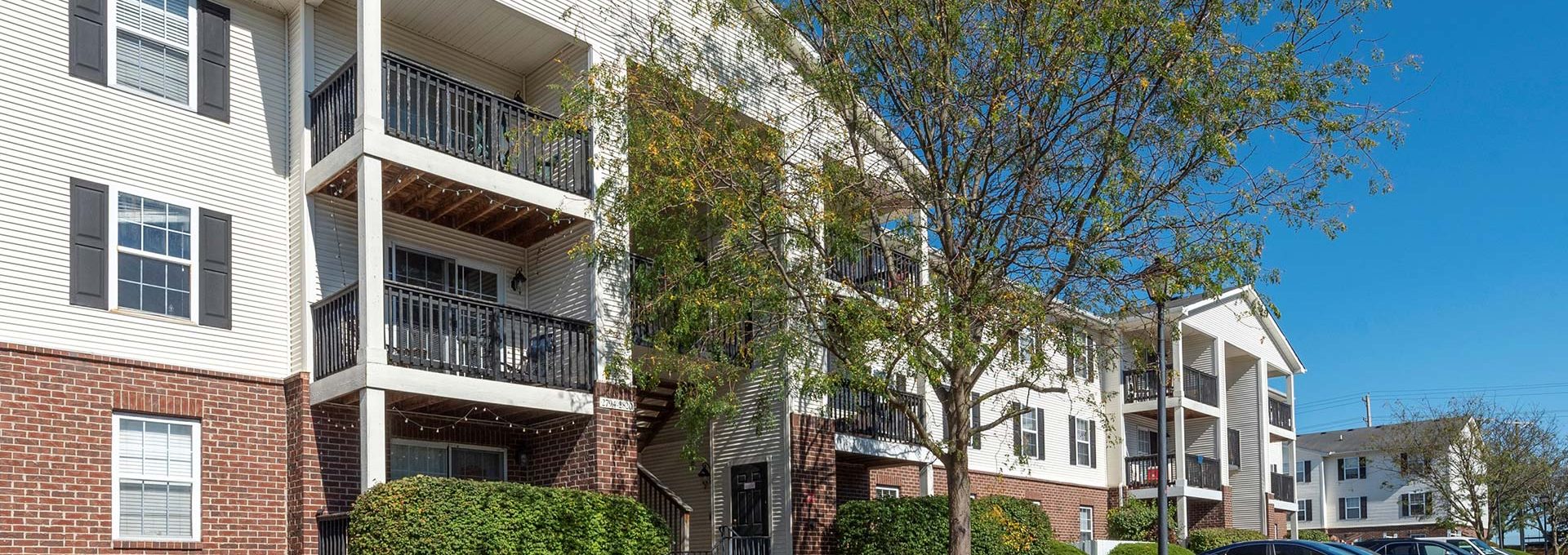 the exterior of an apartment complex with trees and bushes at The Sawmill Park